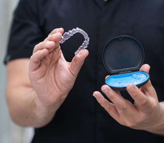 An orthodontist taking clear aligners out of a case