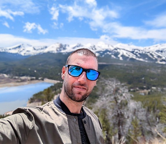Doctor Snider taking a selfie with mountains in the background on a sunny day.