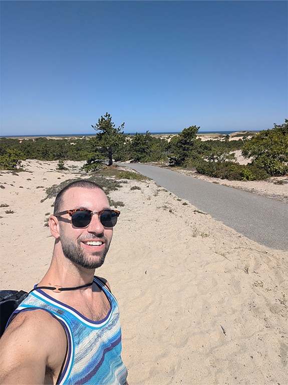 Doctor Snider taking a selfie at the beach in the background on a sunny day.